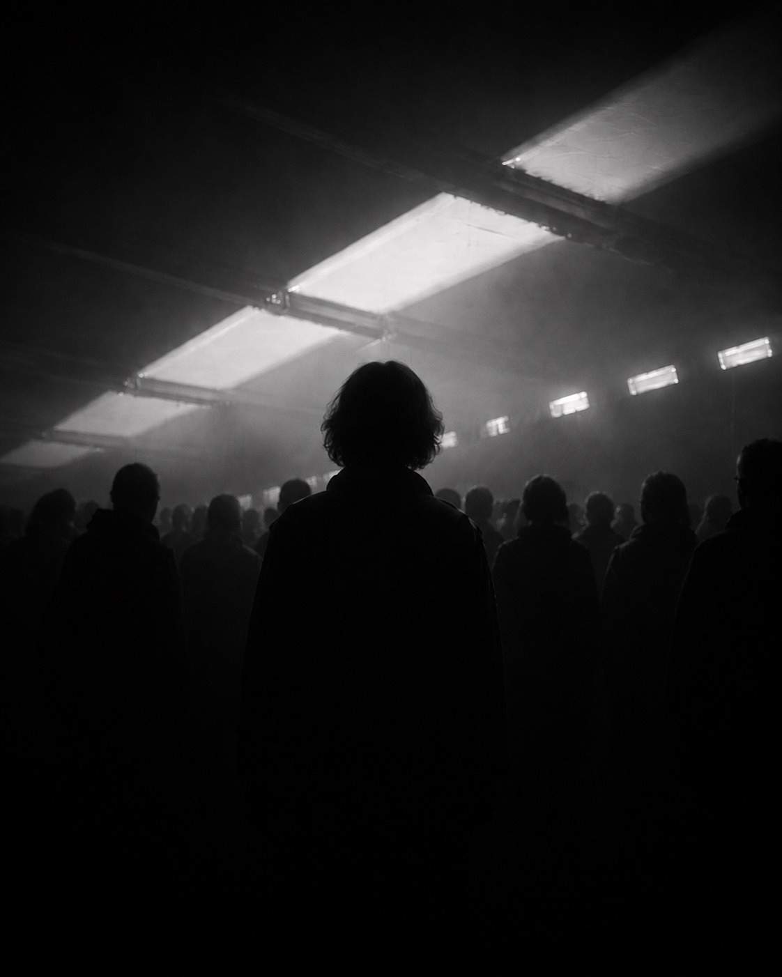 A crowd beneath a grid of light in a dark performance space.